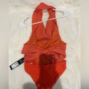 Orange leotard piece with back out and wraps around neck with a bow in the back.